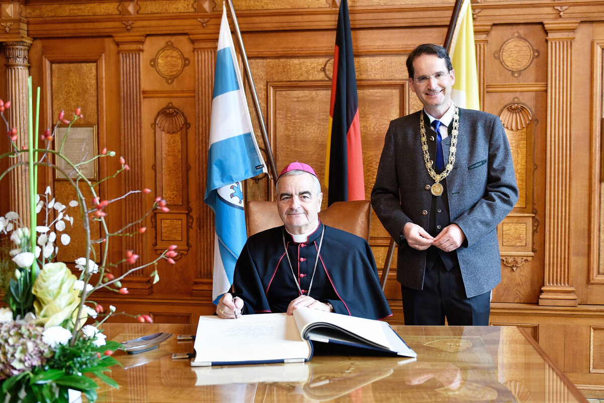 Der apostolische Nuntius trägt sich im Beisein des Oberbürgermeisters ins Goldene Buch der Stadt ein.